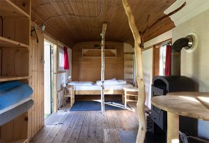 Inneneinrichtung eines Bauwagens. Ausgestattet mit Holzfußboden, einem Bett und einem Holzofen.