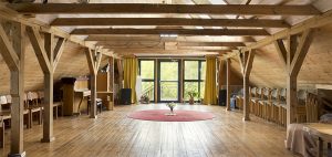 Großer holzverkleideter Raum mit Holzbalken.